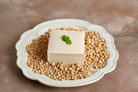 kostka tofu i ziarna soi ułożone na białym talerzu na stole