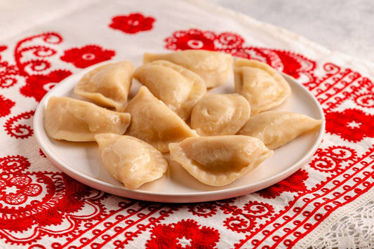 pierogi ułożone na białym talerzyku, leżące na stole z biało-czerwonym obrusem