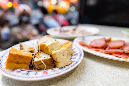 tajwanski street food, jedzenie rozłożone na kolorwych talerzykach w tle tłoczna ulica