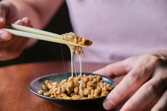 soja natto ułożona w cermiacznej miseczce, podnoszona przez osobę drewnianymi pałeczkami